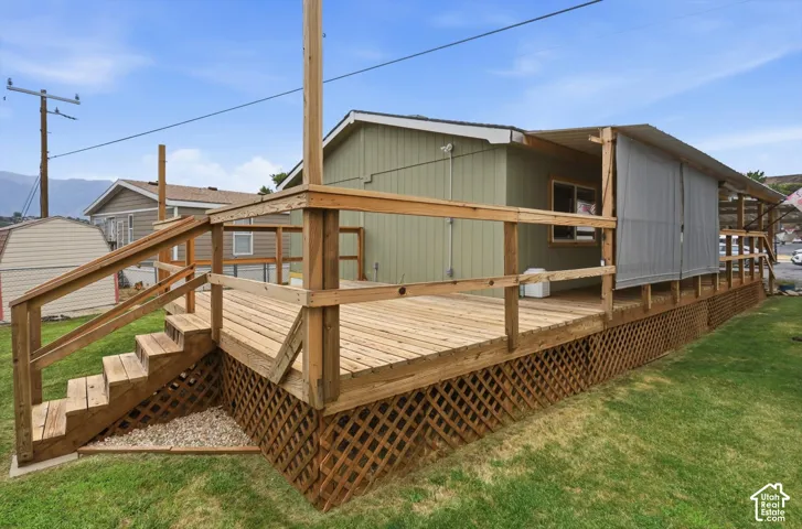 Expansive wood deck with stairs, featuring a partial roof cover, exterior siding, and lattice skirting