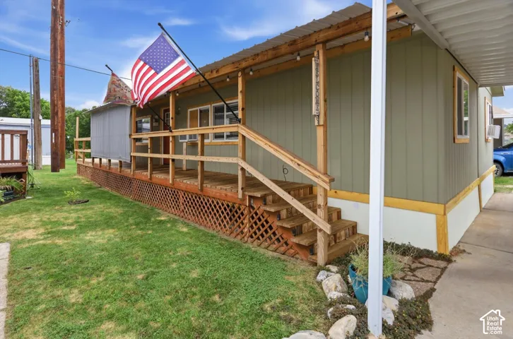 Covered porch with wood steps and railing, lattice skirting, and a corrugated metal roof