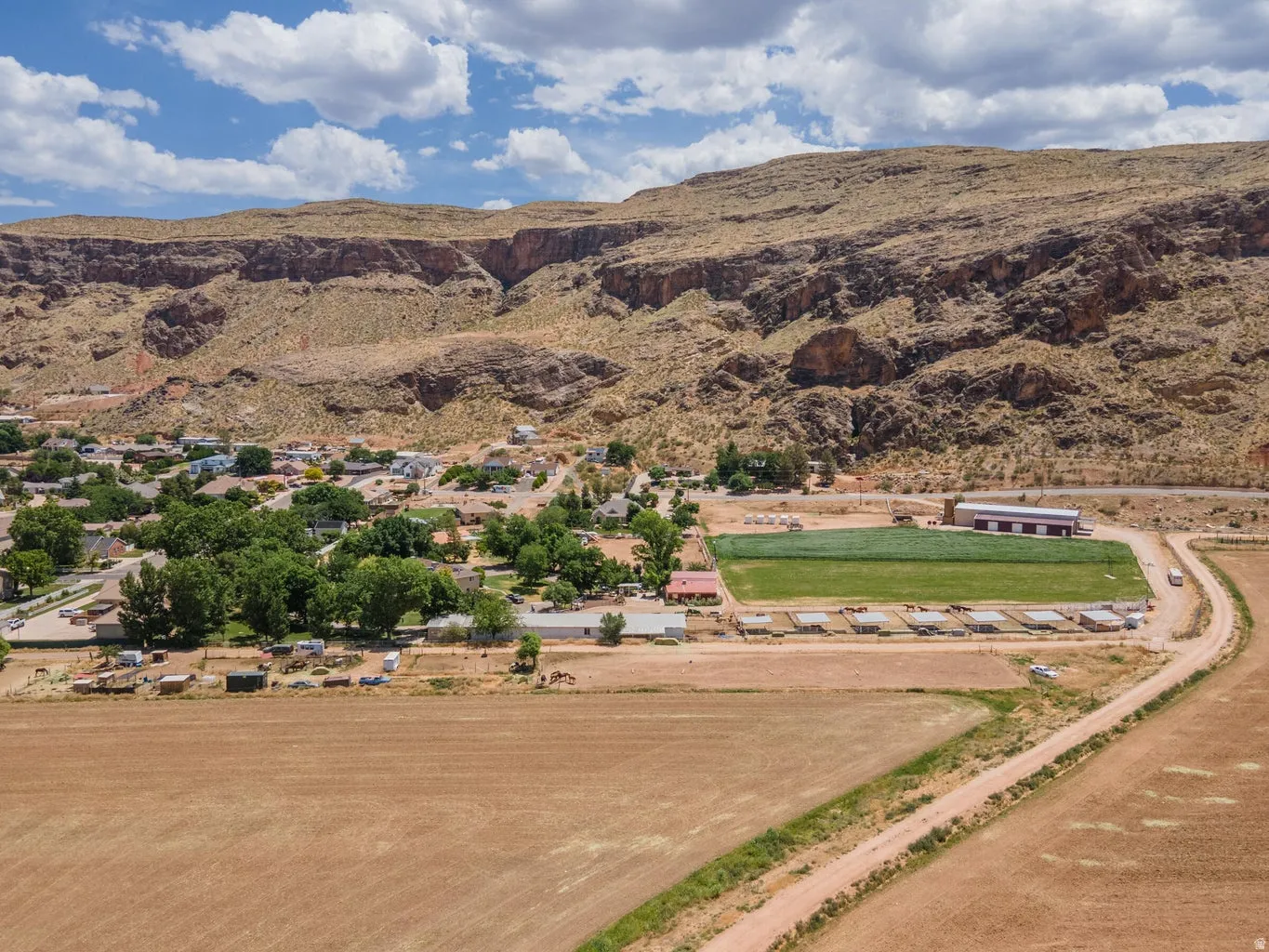 Expansive property featuring undeveloped land, established residential structures, and a prominent mountain backdrop