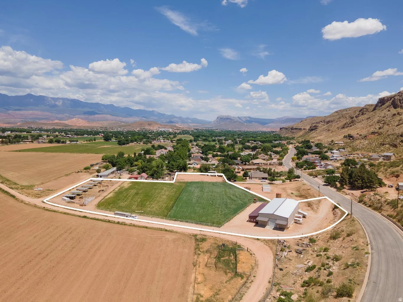Expansive property featuring multiple agricultural fields, a large metal barn, and additional outbuildings