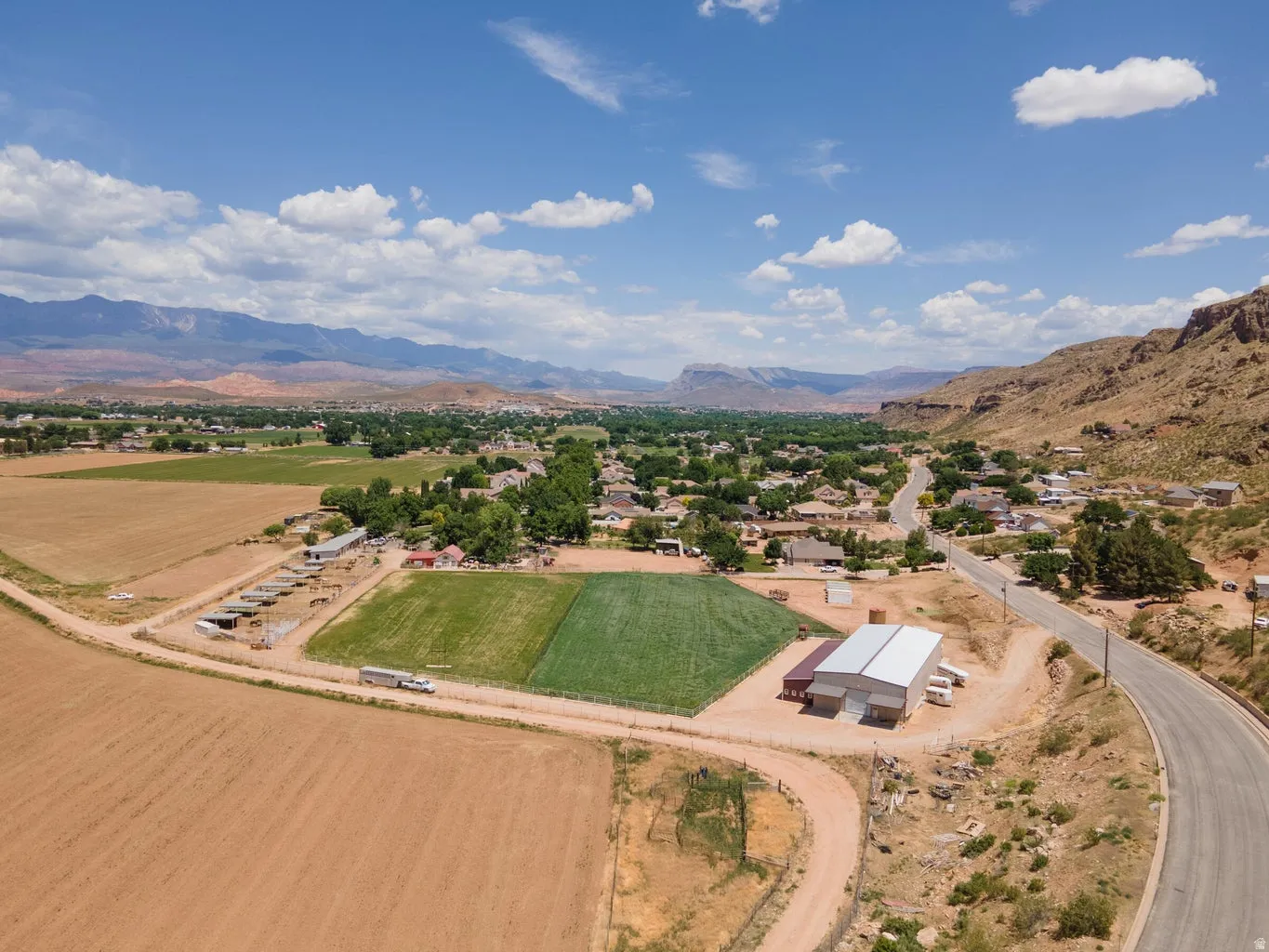 Expansive rural property featuring cultivated fields, multiple outbuildings, and a paved road