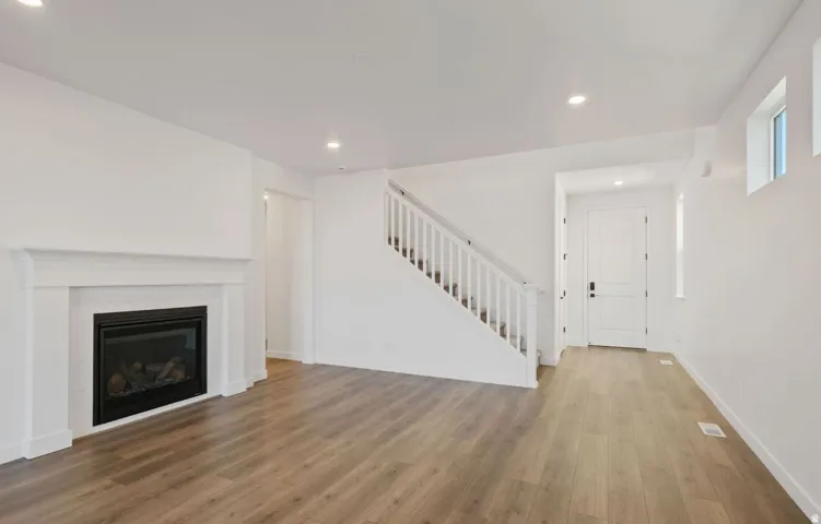 Living area featuring a white mantel fireplace, recessed lighting, and wood-finish flooring