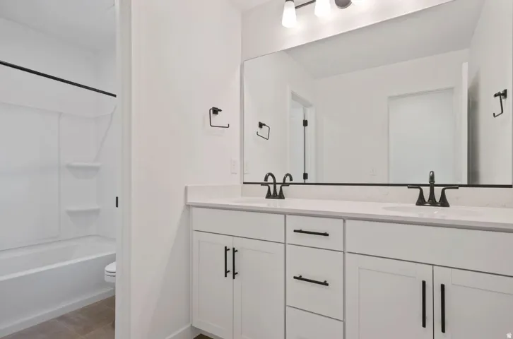 Dual vanity with white cabinetry, matte black hardware, and an expansive wall-mounted mirror