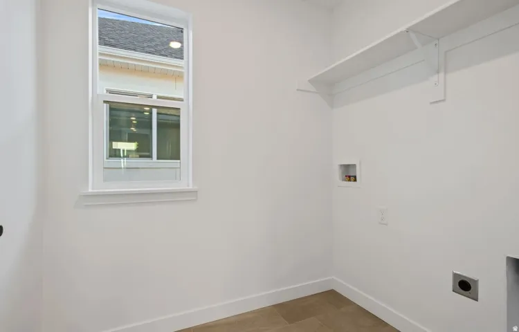 White walls with a window, white shelving, and tile flooring
