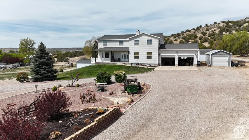 Two-story residence with an attached two-car garage, gravel driveway, and a separate detached garage structure