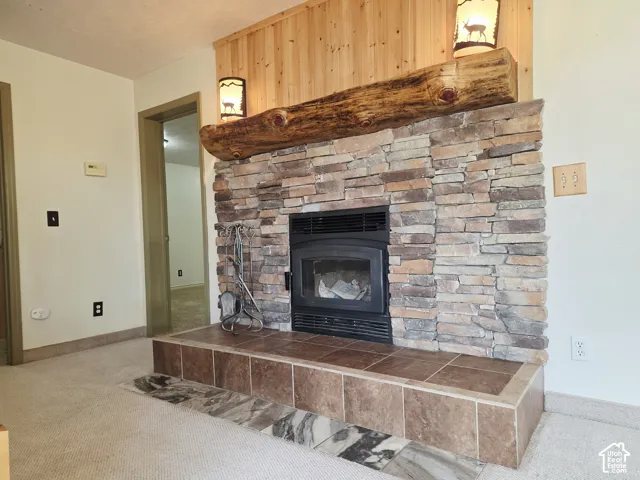 Stone surround fireplace with a wood mantel, integrated wood-burning insert, and a tile hearth with an accent border