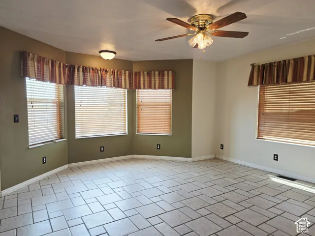 Tiled flooring in a geometric pattern, bay windows with blinds, ceiling-mounted light fixture, and a ceiling fan with light