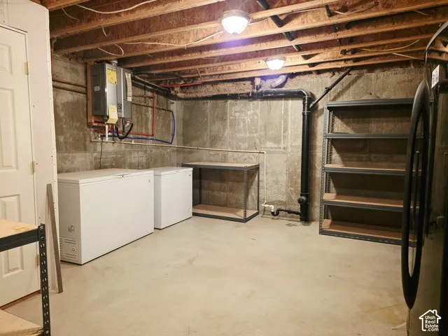 Exposed ceiling joists with utility lighting, concrete flooring, and unfinished concrete walls