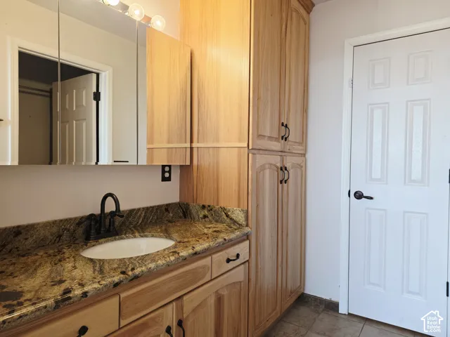 Wood-finish cabinetry with black hardware, granite countertop with integrated sink, and an oil-rubbed bronze faucet