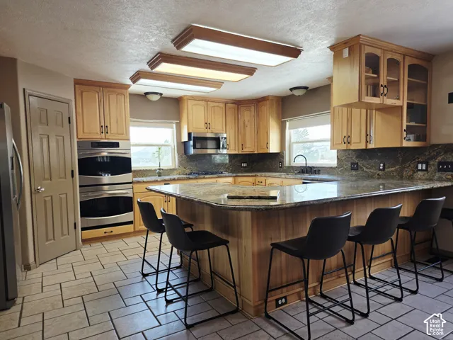 U-shaped kitchen featuring wood cabinetry, granite countertops, stainless steel double ovens, and tile flooring
