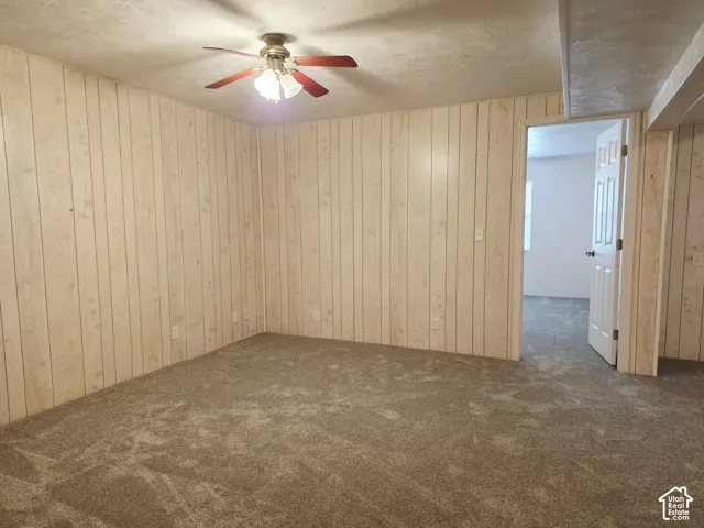 Room with light wood-finish paneled walls and a ceiling fan with integrated lighting