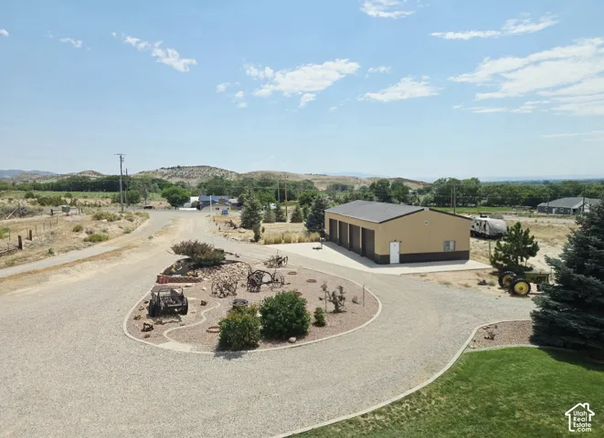 Expansive gravel driveway leading to a multi-bay outbuilding with roll-up doors