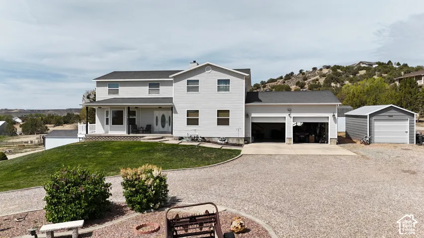 Two-story residence with a covered porch, attached two-car garage, and an additional detached garage structure