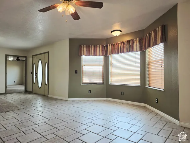 Patterned tile flooring, bay windows, ceiling fan, flush-mount lighting, and an oval-paneled entry door