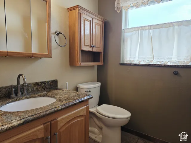 Vanity with granite countertop, integrated sink, and bronze-finish faucet