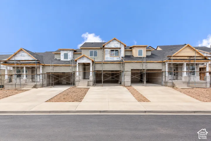 Multi-unit residential structure featuring a shingle roof, stone and stucco facade, covered front porches, and multiple concrete driveways