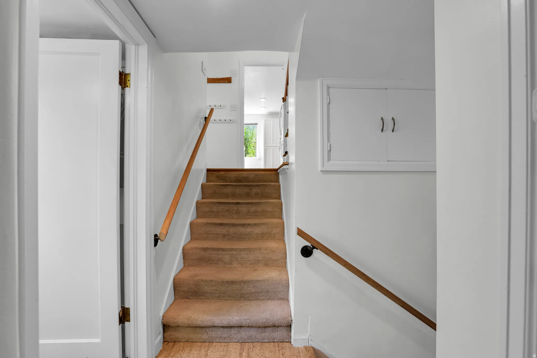 Carpeted staircase with light wood-finish handrails leading to an upper level
