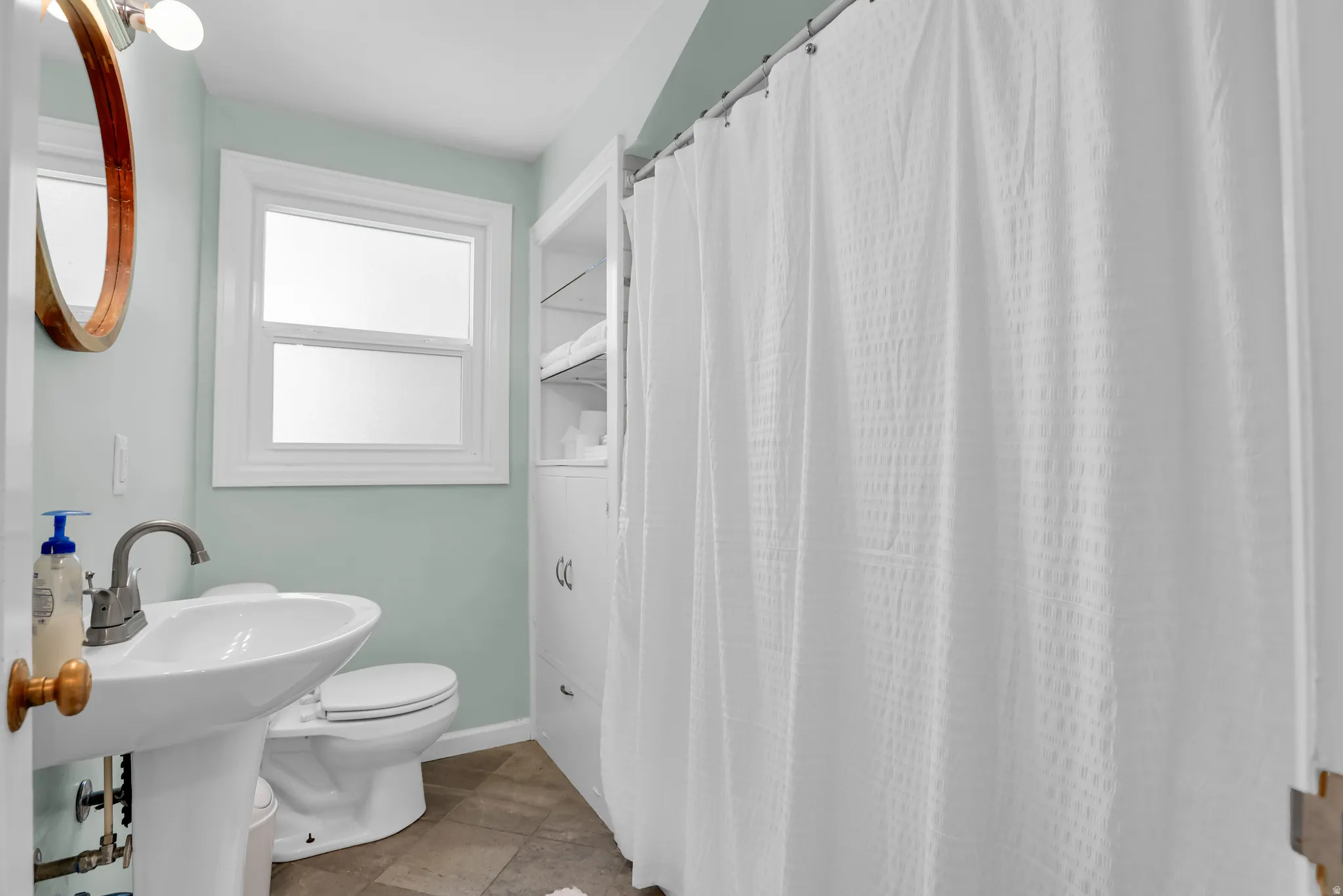Bathroom featuring a pedestal sink, white toilet, and built-in white storage cabinetry