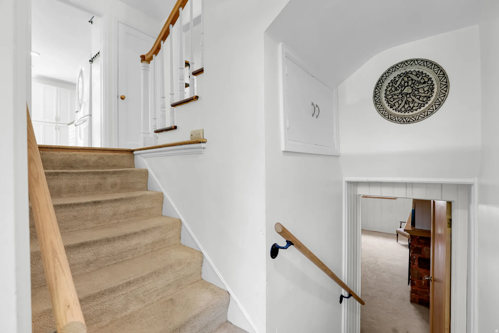 Carpeted staircase with light wood handrails and white balusters