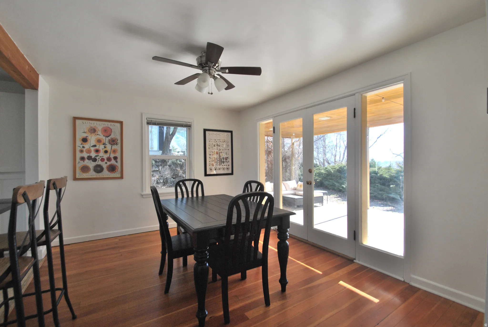 Wood-finish flooring, white walls, ceiling fan with integrated lighting, and white-framed glass paneled doors