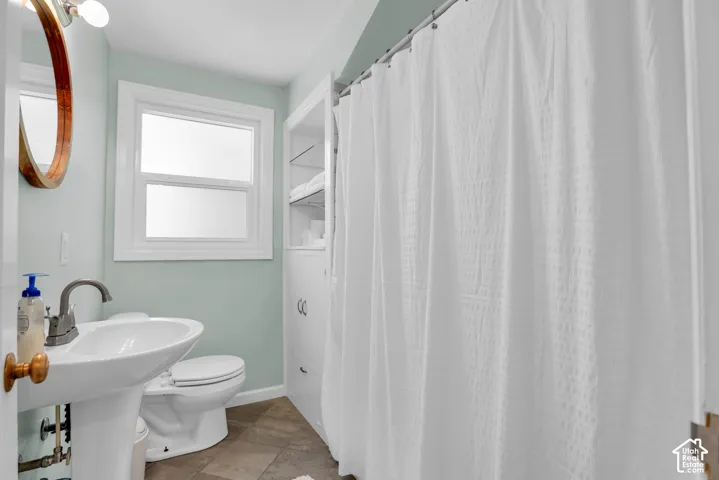 Bathroom featuring a pedestal sink, white toilet, and built-in white storage cabinetry