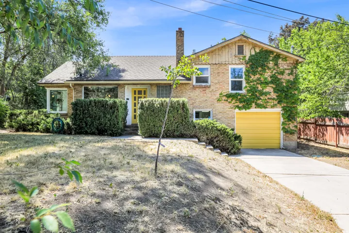 Brick facade residence featuring a prominent yellow entry door and coordinating garage door