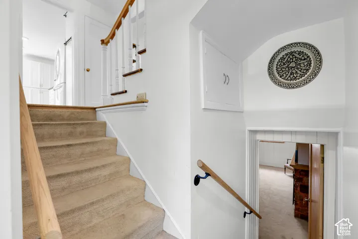 Carpeted staircase with light wood handrails and white balusters