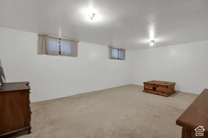 Spacious room with white walls, two windows, recessed lighting, and carpeting throughout