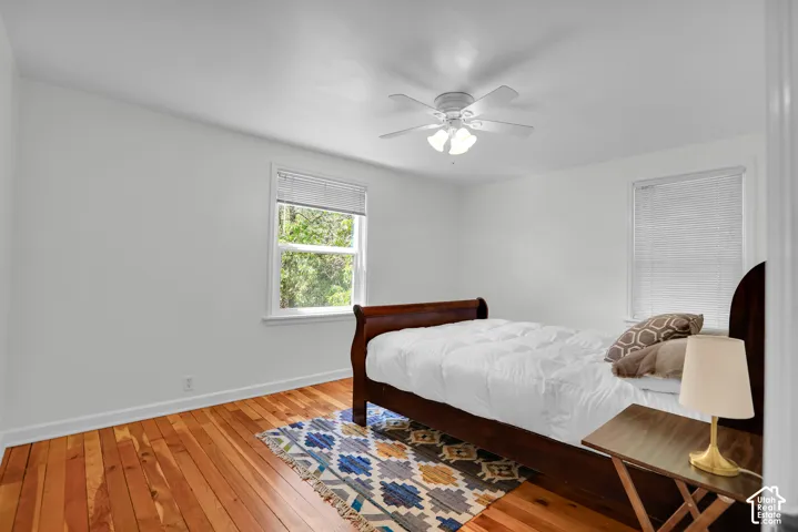 Bright interior featuring natural wood flooring, a ceiling fan with integrated lighting, and white walls