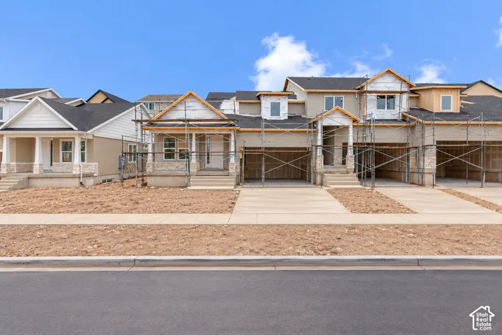 Multi-unit residential exterior featuring mixed-material siding, masonry accents, pitched shingle roofing, and attached multi-car garages