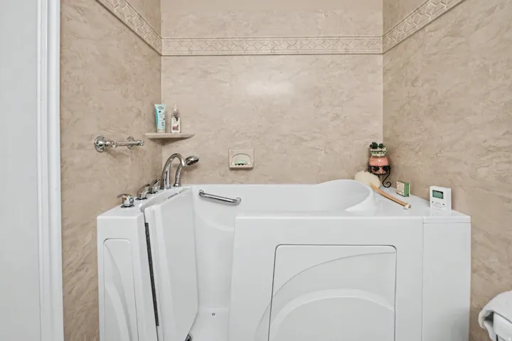 Walk-in bathtub with integrated grab bar and chrome fixtures