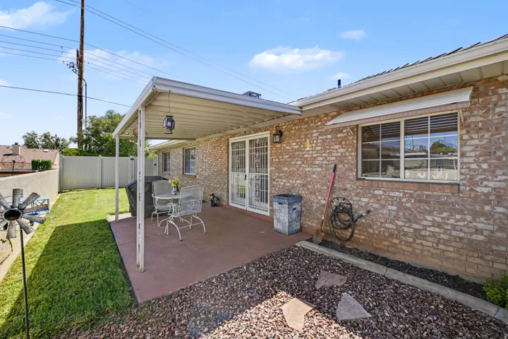 Brick exterior with a covered patio, concrete patio surface, and a fenced yard