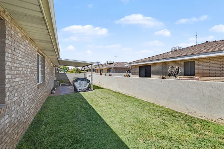 Expansive backyard featuring a manicured lawn, a concrete patio, and a covered patio area