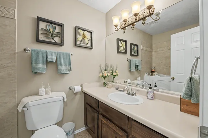 Spacious vanity with an integrated sink, broad countertop, wood-finish cabinetry, and an expansive wall-mounted mirror