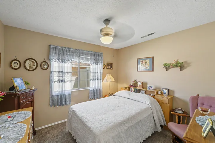 Carpeted flooring, a window with horizontal panes, and a ceiling fan with integrated lighting