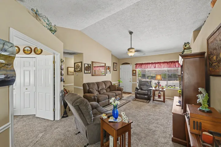 Vaulted ceiling, ceiling fan, carpet flooring, dual closet doors, and front entry door