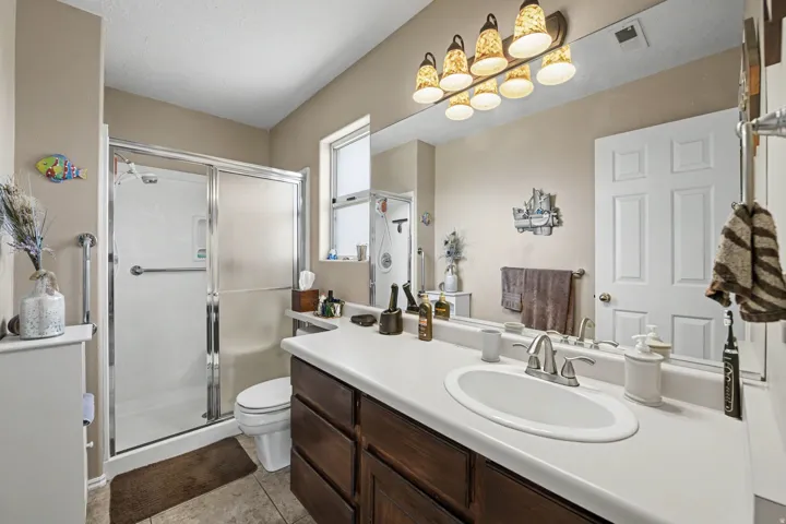 Full-width vanity with an integrated sink, dark wood-finish cabinetry, and a multi-bulb light fixture