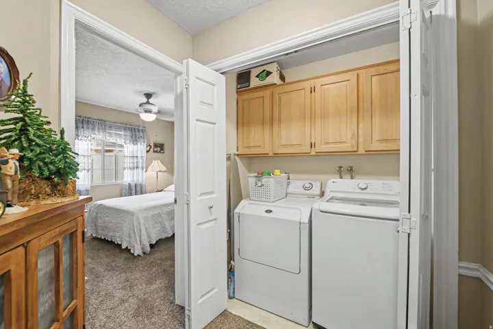Built-in laundry closet with wood upper cabinetry, washer, and dryer