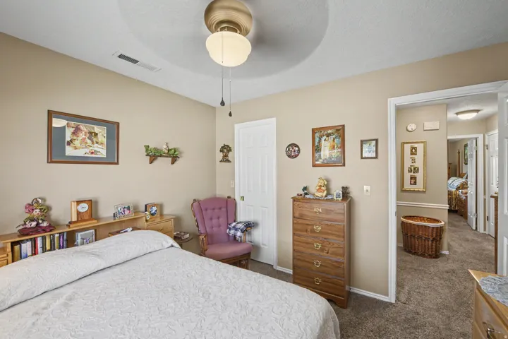 Textured carpet flooring, ceiling fan with integrated lighting, door with white trim, and light beige wall paint