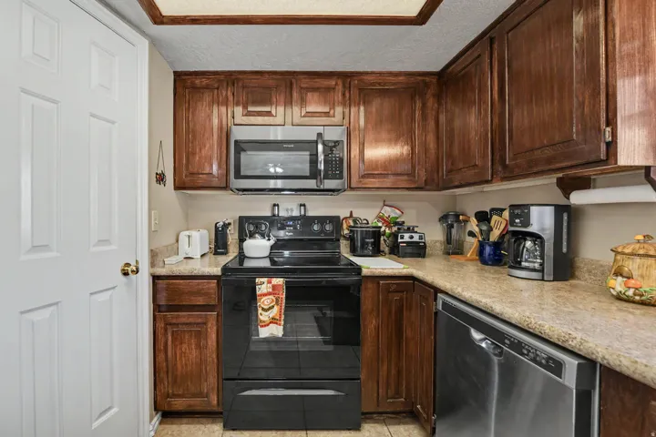 Wood-finish cabinetry paired with a built-in stainless steel microwave and a black electric range