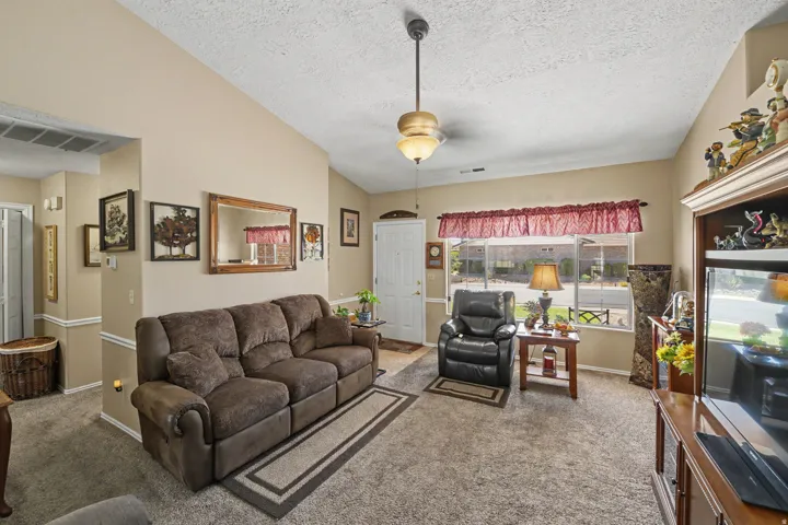 Vaulted ceiling with pendant lighting, front entry door, large front-facing window, and neutral wall tones