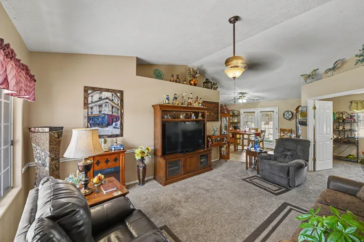 Vaulted ceiling with pendant lighting, integrated shelving, and carpeted flooring
