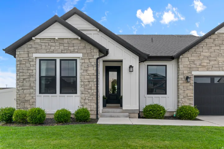Stone veneer and board-and-batten siding exterior with a dark-framed entry door