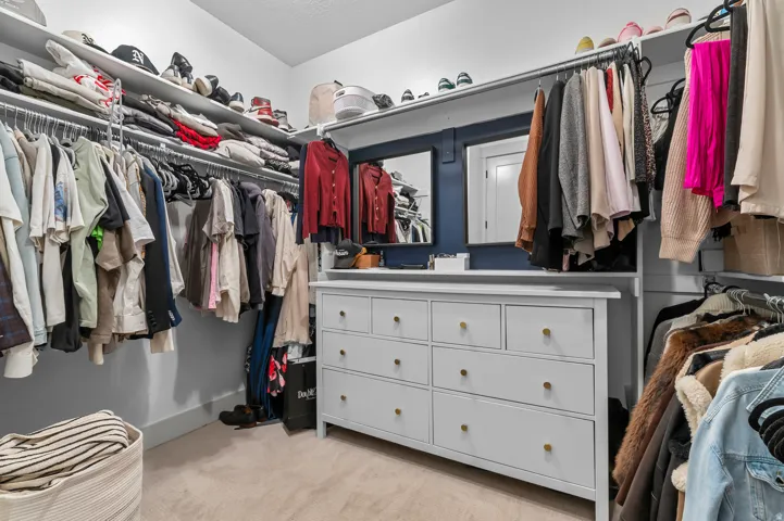 Custom closet system with white shelving, hanging rods, and an integrated dresser