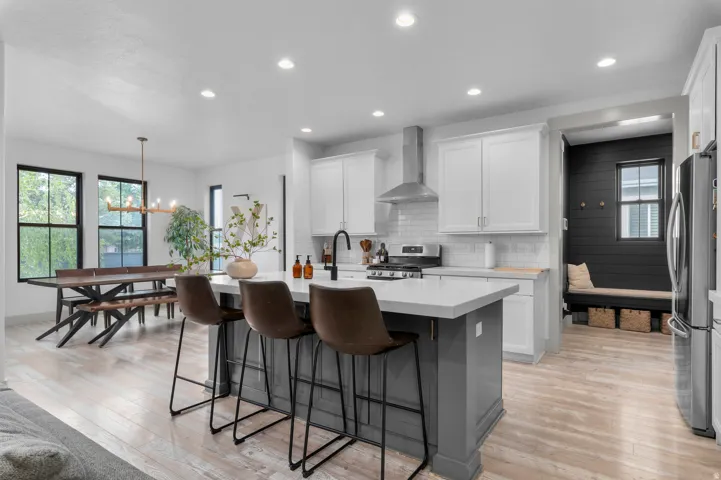 Kitchen featuring white cabinetry, stainless steel appliances, a white subway tile backsplash, and a large island with a light-toned countertop