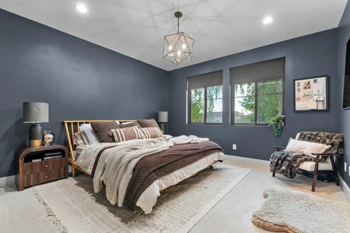 Recessed lighting, contemporary chandelier, two large windows with roller shades, wood-finish flooring, and dark accent walls