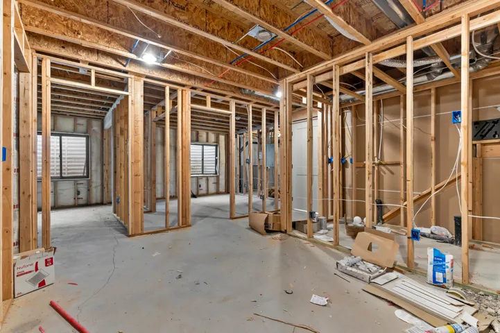 Unfinished space with framed walls, exposed ceiling joists, concrete flooring, and multiple windows