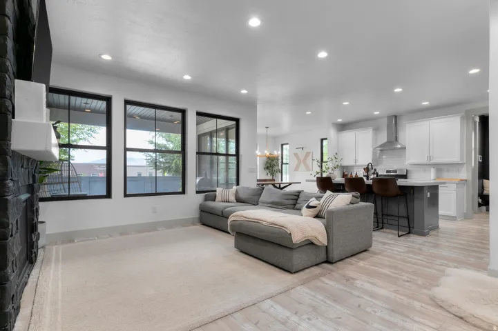 Open-concept living area with recessed lighting, wood-finish flooring, and a stone-clad fireplace