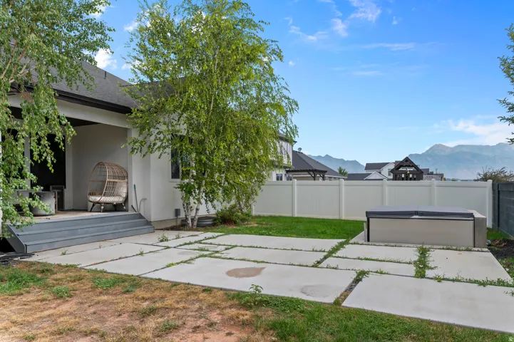 Outdoor patio with large format concrete pavers, mature trees, and a built-in spa