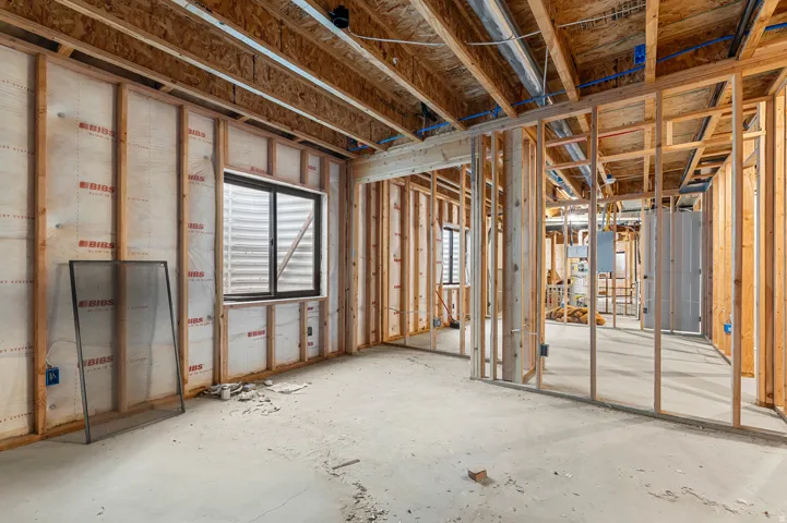 Framed interior with visible insulation, exposed ceiling joists, and concrete flooring